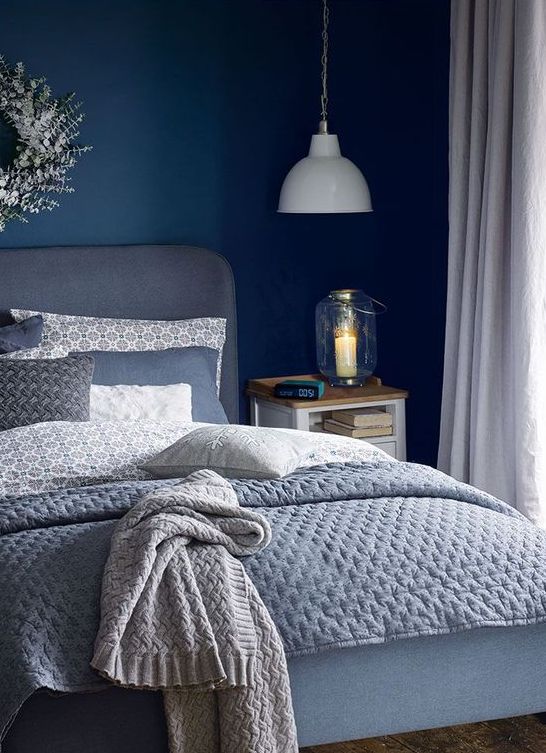 a relaxing bedroom with grey as a dominant color and navy as a bold accent one