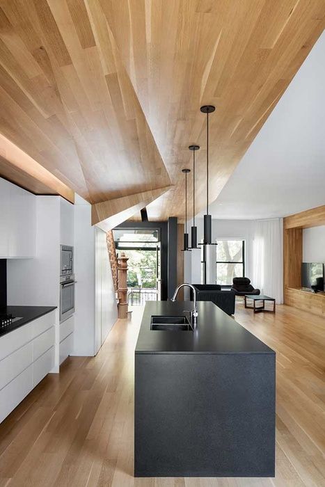 a minimalist white kitchen plus a sleek black kitchen island and a geometric ceiling for a wow effect