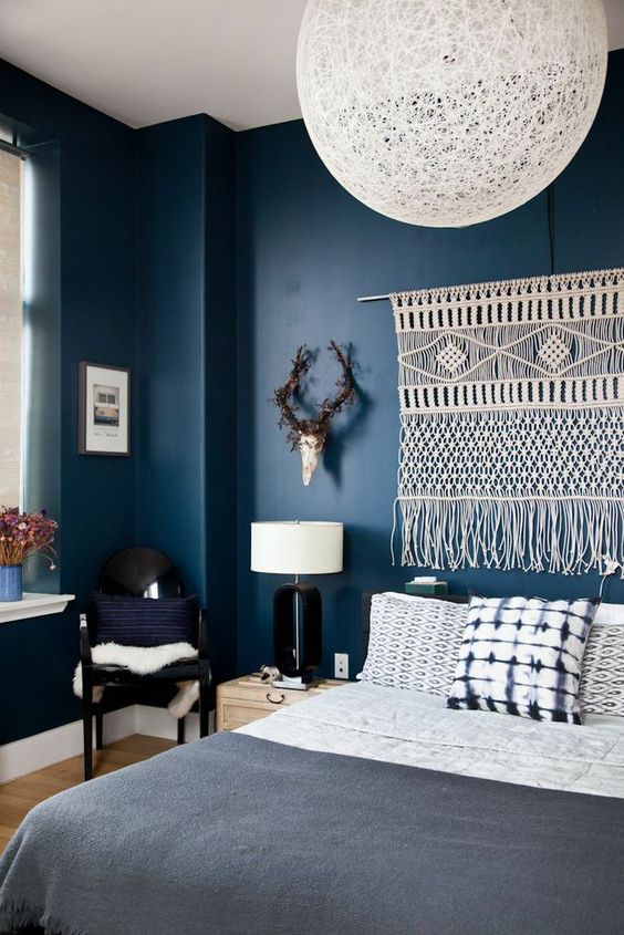 deep blue walls can be refreshed with various white accents like a macrame hanging and a yarn lampshade
