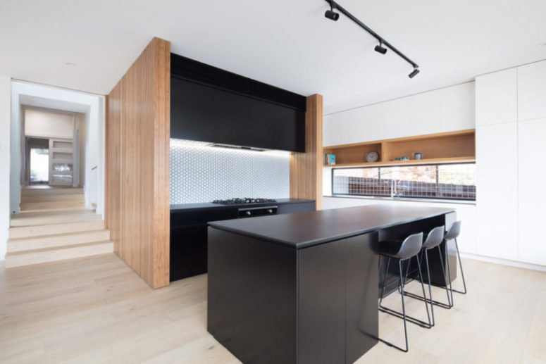 kitchen with penny tiles The kitchen is done with black cabinets and light-colored wood, the backsplash is clad with penny tiles