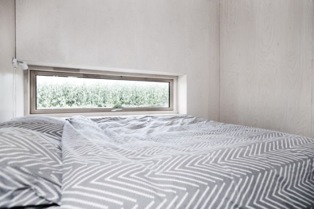 Above there's a small bedroom with a narrow window, a large bed and some box shelves