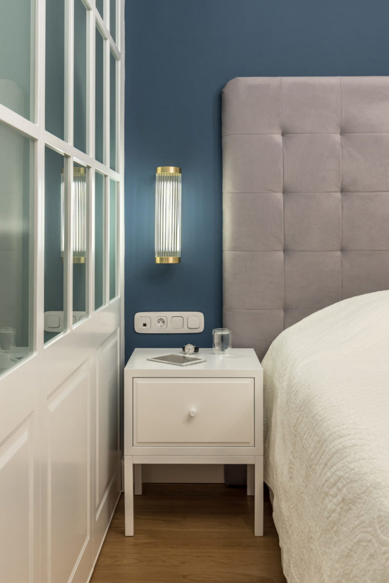 The master bedroom is done in neutrals, with a large upholstered bed and a muted blue statement wall