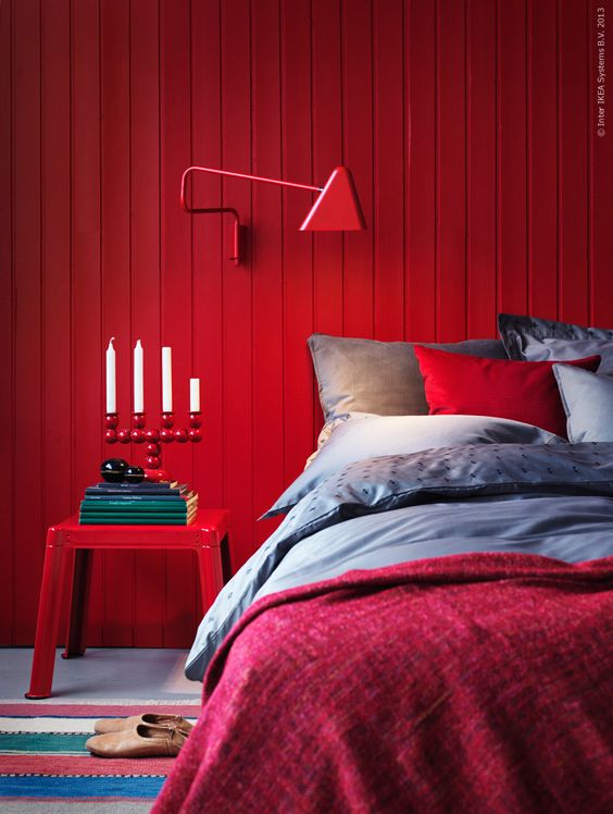 a red wooden plank wall, a matching sconce and a nigthstand create a super colorful space