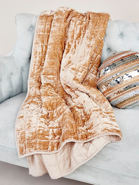 an orange crushed velvet blanket and a matching boho round pillow