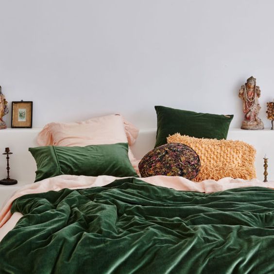 a bright and welcoming bed with a boho feel with green velvet and a woven fringe pillow