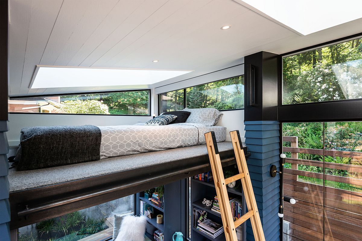 A ladder invites to a small sleeping space up, a bed with a skylight and windows on each side
