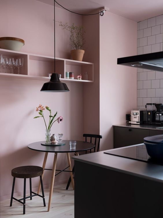 a rose statement wall highlights the dining space and softens the black cabinets and furniture