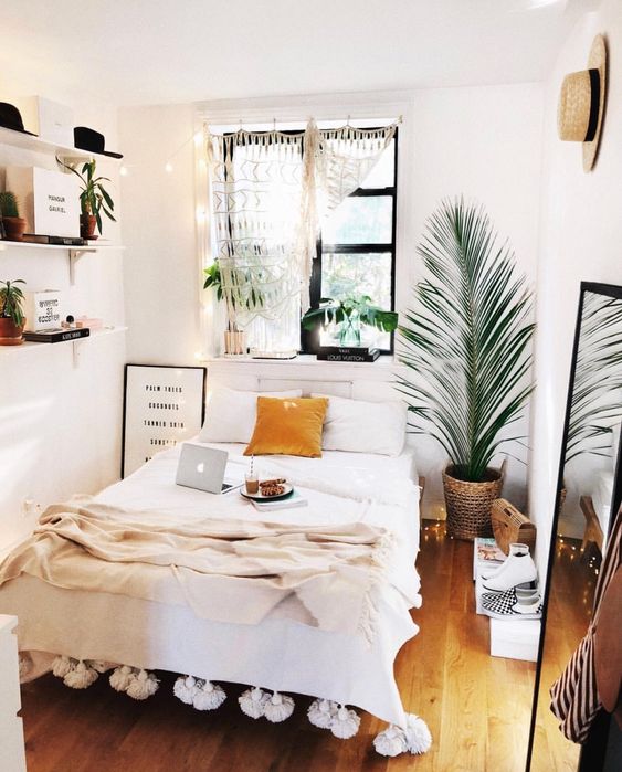a boho chic feel is achieved with a neutral color scheme, macrame and tassels and some hats on the walls