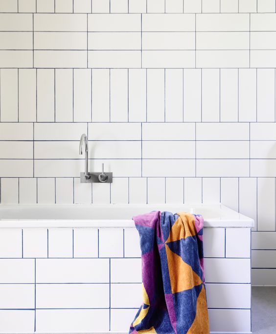 a minimalist bathroom with white tiles and bold blue grout to highlight the tiles and patterns