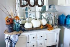 10 a vintage console with a trio of white pumpkins, fall leaves and a plaid blanket