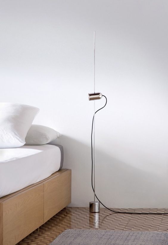 a minimalist floor lamp with a thin metal base and a small spotlight for a minimalist bedroom
