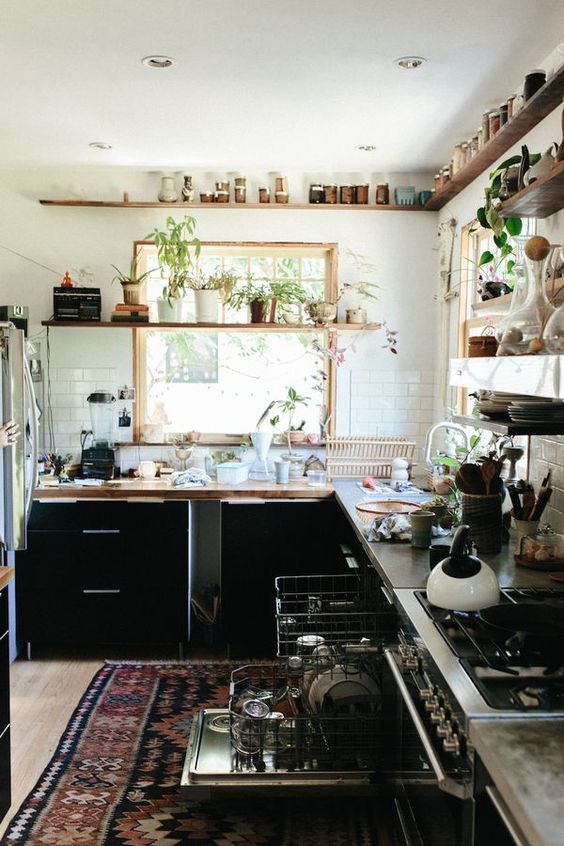 a kitchen with lots of plants, a boho rug and wooden shelves for a natural feel
