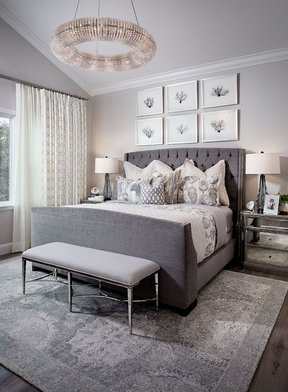 a bedroom in different shades of grey is spruced up with a seaside gallery wall and a large crystal chandelier