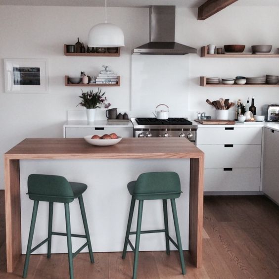 a minimalist waterfall kitchen island in white with a wooden countertop and colorful stools