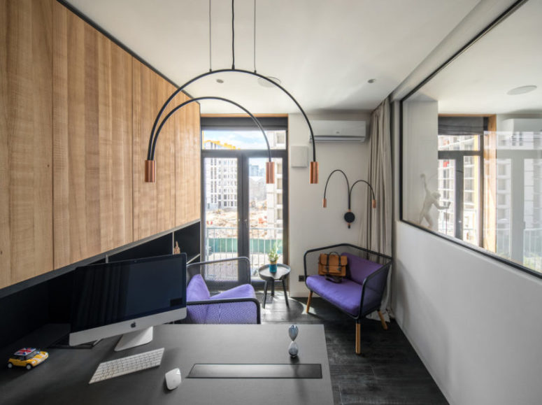 The home office shows off catchy purple chairs and unique arch hanging lamps