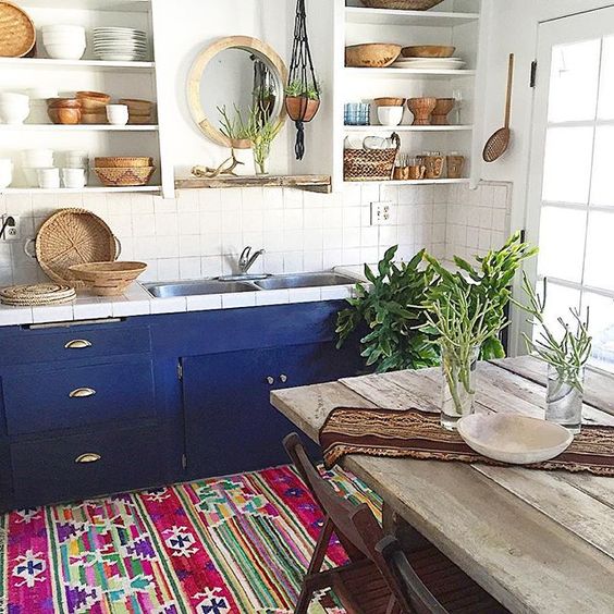 a boho chic kitchen with wooden and wicker touches plus a colorful boho rug and bold cabinets