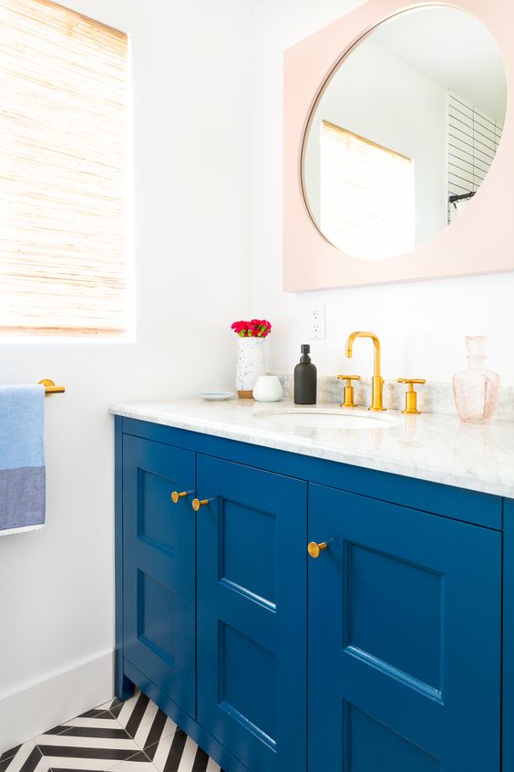 an electric blue vanity with molding and brass fixtures to add color to the space