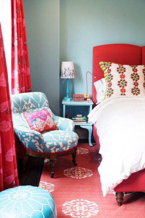 a red carpet, a red upholstered bed and red printed curtains contrast the blue bedrooms and furniture