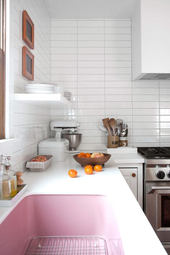 a serene white kitchen with a pink sink that adds interest and color to the space