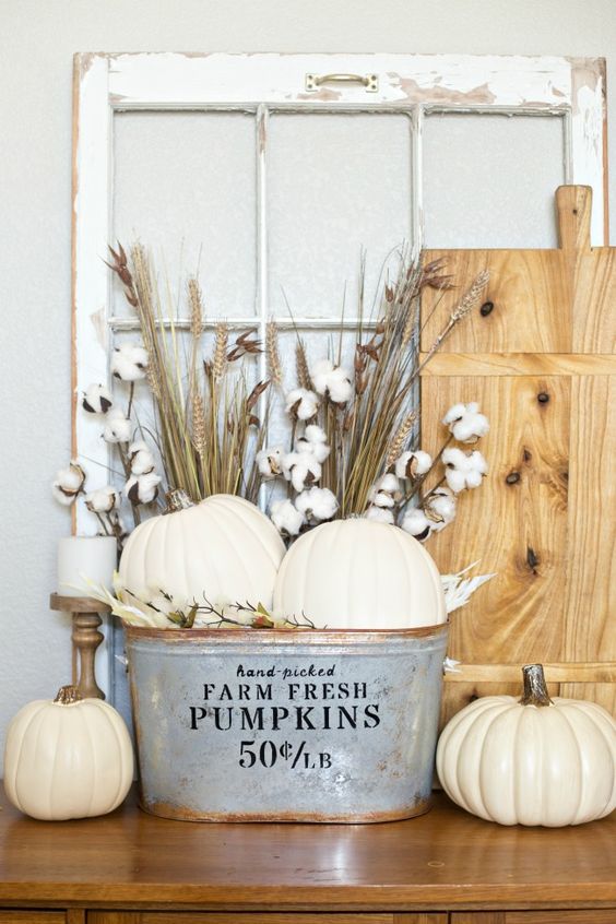 a farmhouse display with white pumpkins, wheat and cotton in a metal bathtub