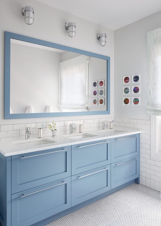 a large modern pale blue triple vanity with silver handles and a matching large mirror for a coastal feel
