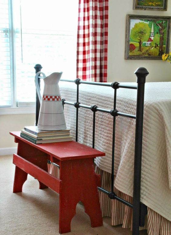 a simple red bench at the footrest is a creative idea for storage and adding a farmhouse feel