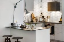20 a small white kitchen island with a black countertop and black industrial stools for having breakfasts