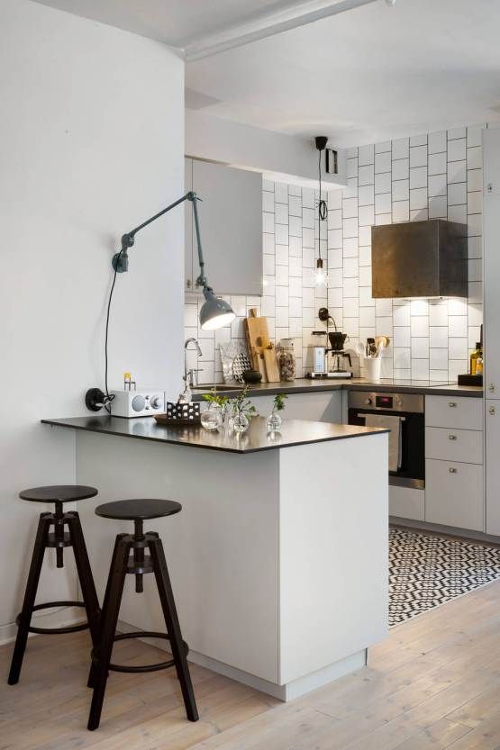 a small white kitchen island with a black countertop and black industrial stools for having breakfasts
