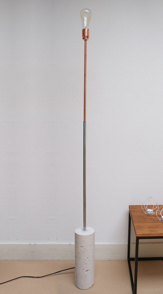a minimalist floor lamp with a concrete base, abrass leg and a bulb, no lampshade