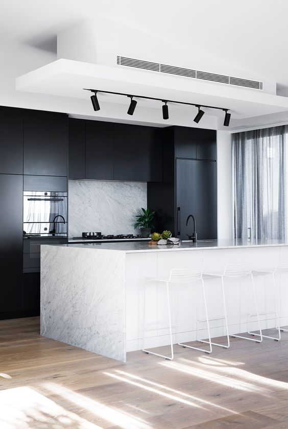 sleek black cabinets plus a white ktichen island with a stone countertop that echoes with the backsplash