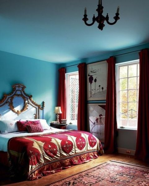 burgundy curtains, pillows and a bedspread contrast the blues and create a unique space