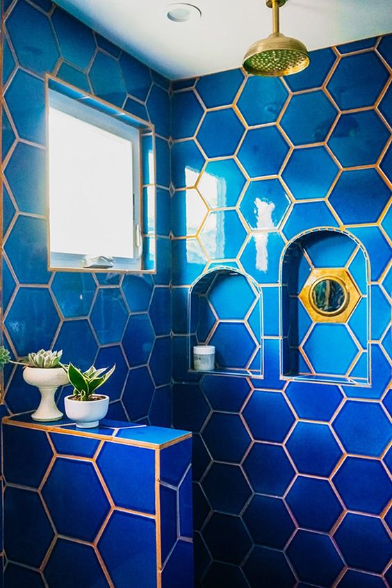 bright blue hexagon tiles with gold grout that highlights the gold fixtures and creates a contrast
