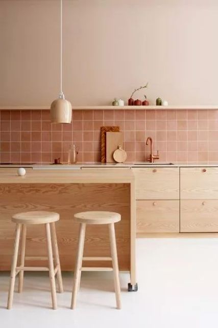 a beautiful modern kitchen with stained cabinets, a dusty pink square tile backsplash, a kitchen island of wood and wooden stools, pendant lamps