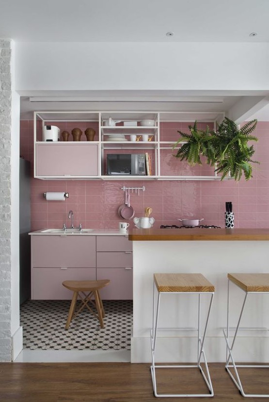 a catchy kitchen with a pink tile backsplash and pale pink cabinets, open shelving and a large white kitchen island