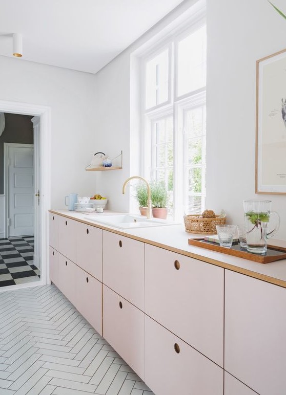 a delicate blush kitchen with only lower cabinets and white countertops plus much natural light