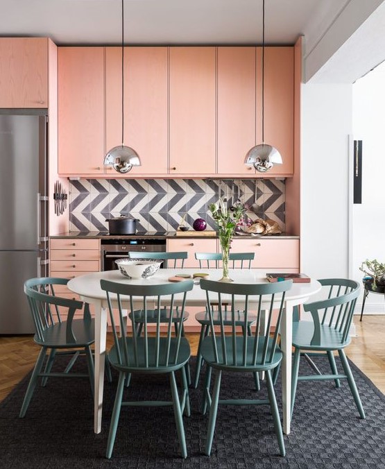 a light pink mid-century modern kitchen with a graphic tile backsplash and a dining zone in blue right here