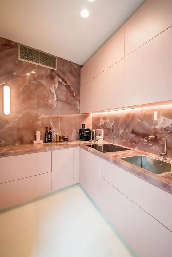 a luxurious minimalist kitchen in pink, with a pink marble backsplash and countertops plus built-in lights