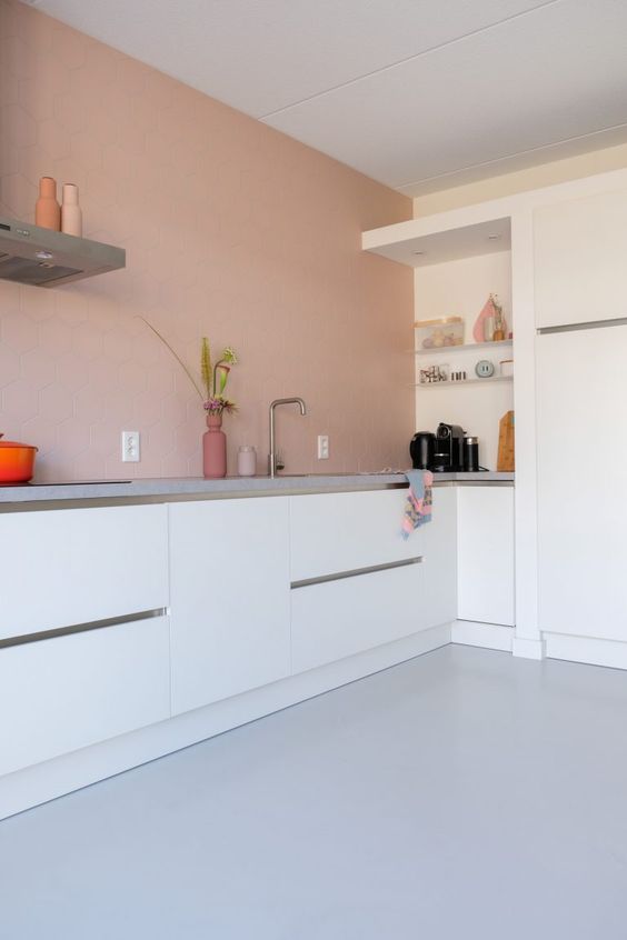 a minimalist kitchen in dusty pink, with sleek white cabinets, grey stone countertops is a chic and lovely space