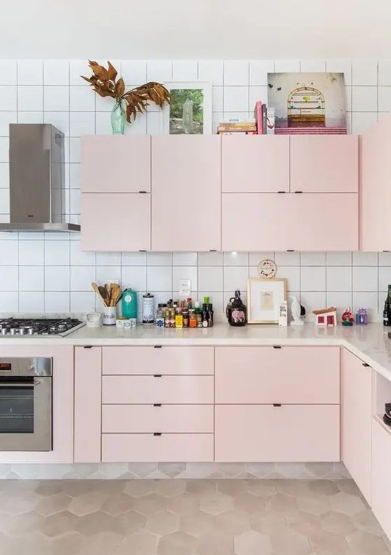 a modern kitchen in light pink, with a white tile backsplash and built-in appliances is all the chic