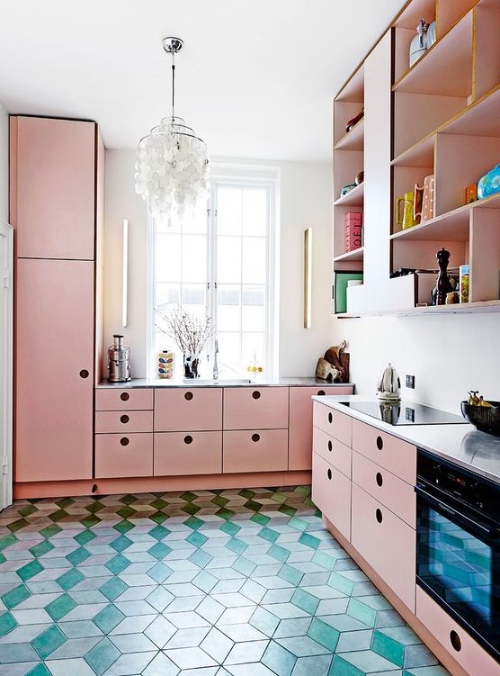 a modern kitchen in pink, with sleek cabinets, a catchy chandelier and a green tile floor is very bold