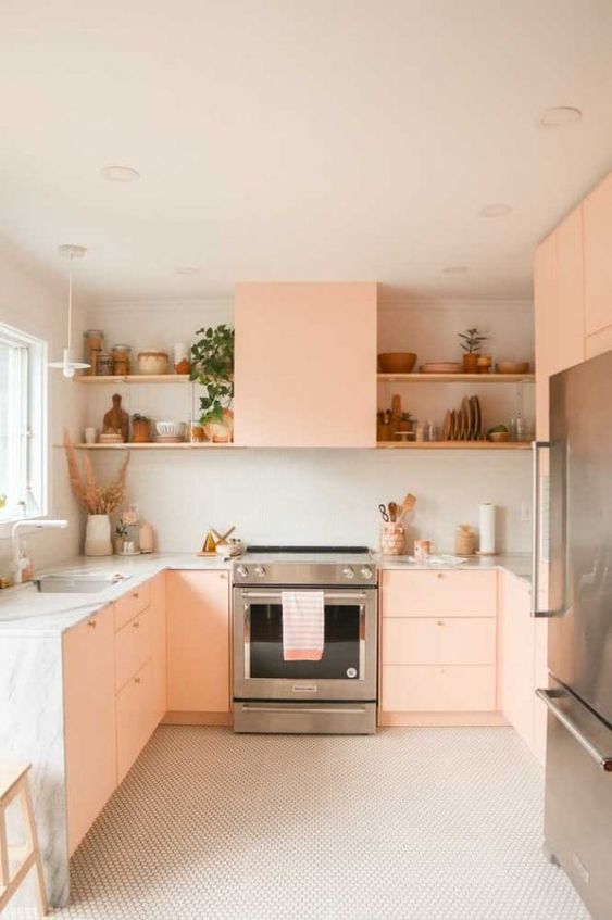 a peachy pink kitchen with neutral stone countertops, open shelves and some lovely decor is a very cozy space