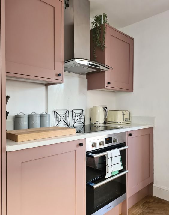 a stylish mauve kitchen with shaker cabinets, built-in appliances, a white stone countertop and a white backsplash is lovely