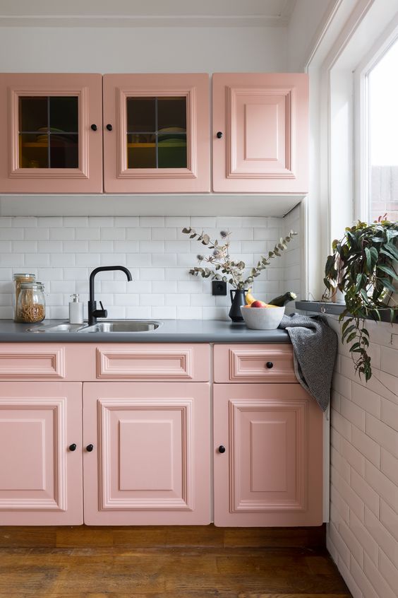 a stylish pink kitchen with shaker cabinets, a white subway tile backsplash, grey stone countertops, black fixtures