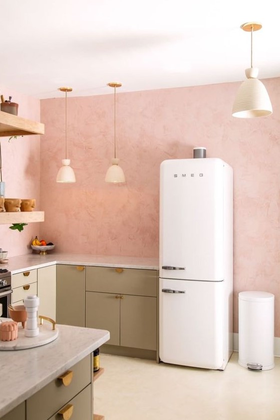 a welcoming kitchen with pink walls, green cabinets, gold handles, pendant lamps and open shelving
