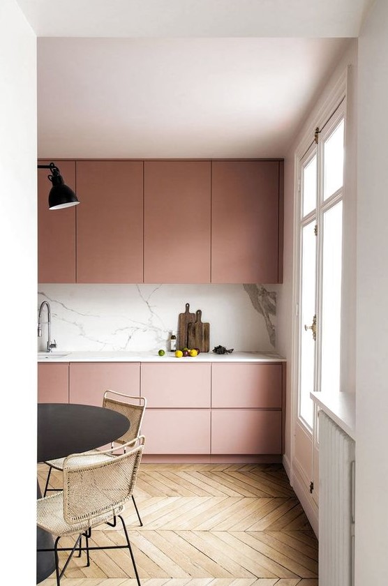 an ultra-minimal dusty rose kitchen with sleek cabinets, a white marble backsplash and countertops plus touches of black