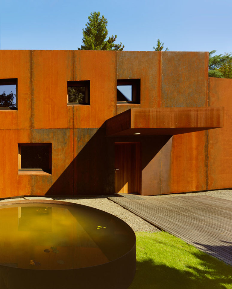 The house is clad with rust-colored metal, which is highlighted with naturally neutral surroundings