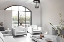 02 The living room is a light-filled space with white furniture and much light coming through an arched window