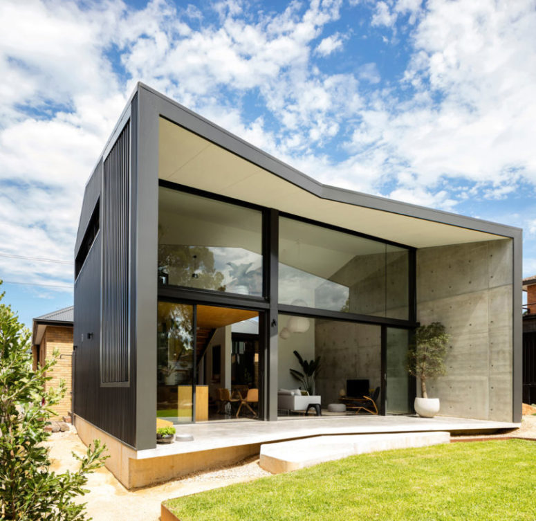 The shape of the pavilion is geometric, clad with dark wood