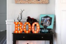 02 a small console table with colorful faux pumpkins, a lit up pumpkin and marquee letters for a bold look