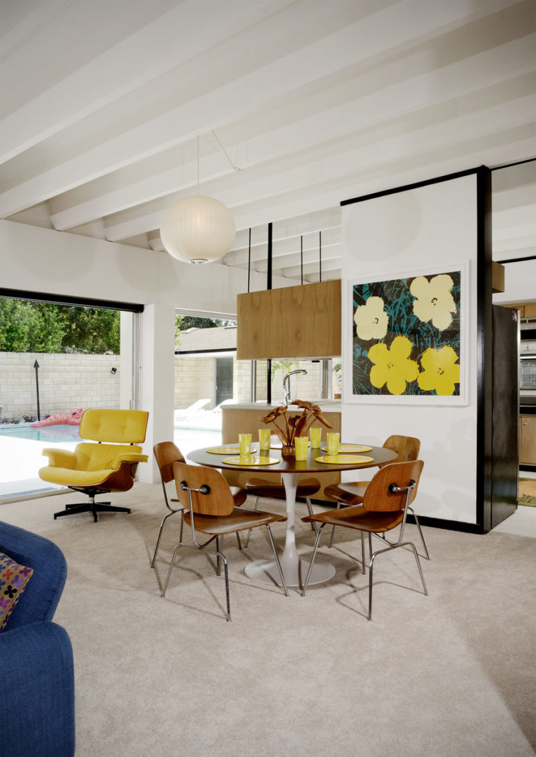 The dining space is done with a round table and chairs and a bright artwork and is separated with a narrow wall The dining space is done with a round table and chairs and a bright artwork and is separated with a narrow wall